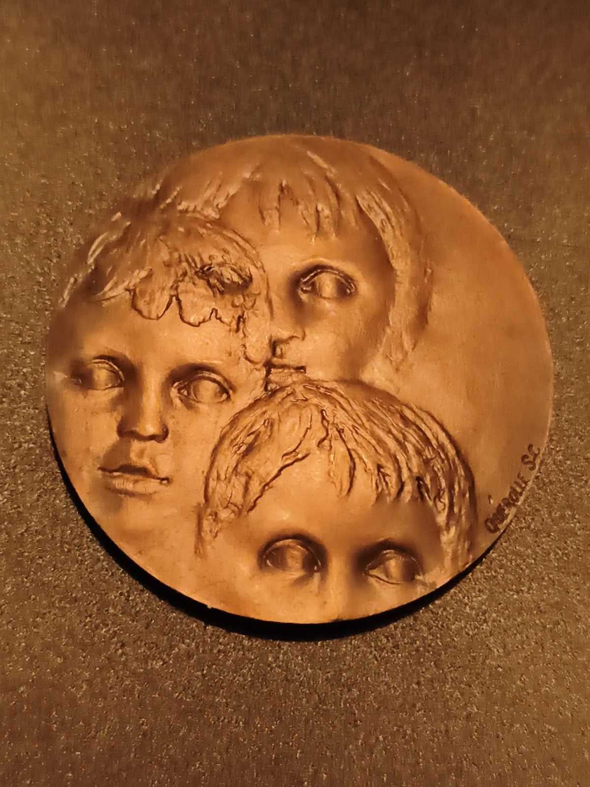 Médaille ronde trois visages enfants signée CROCQUE SC aspect bronze relief
