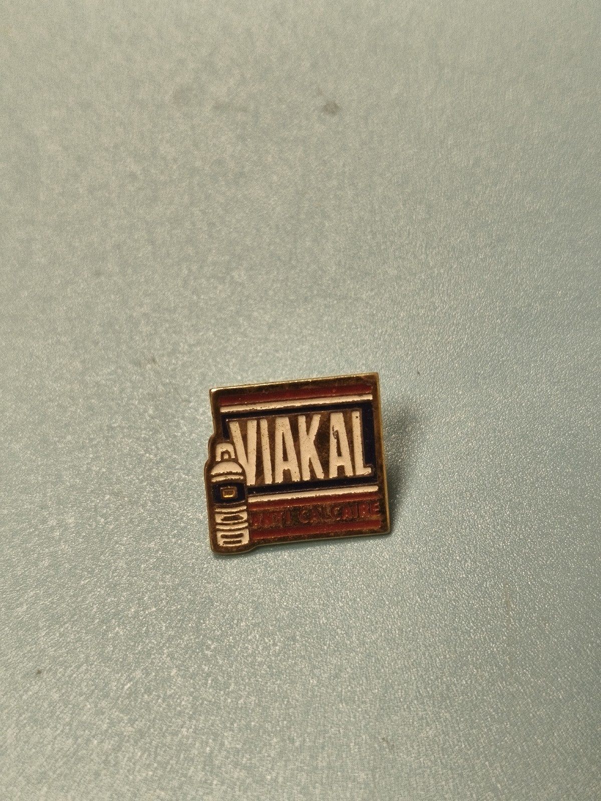 Pin's publicitaire vintage Viakal anti-calcaire, carré, couleurs bleu et rouge