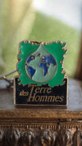 Pin's vintage Terre des Hommes émaillé vert bleu noir, badge ancien rare