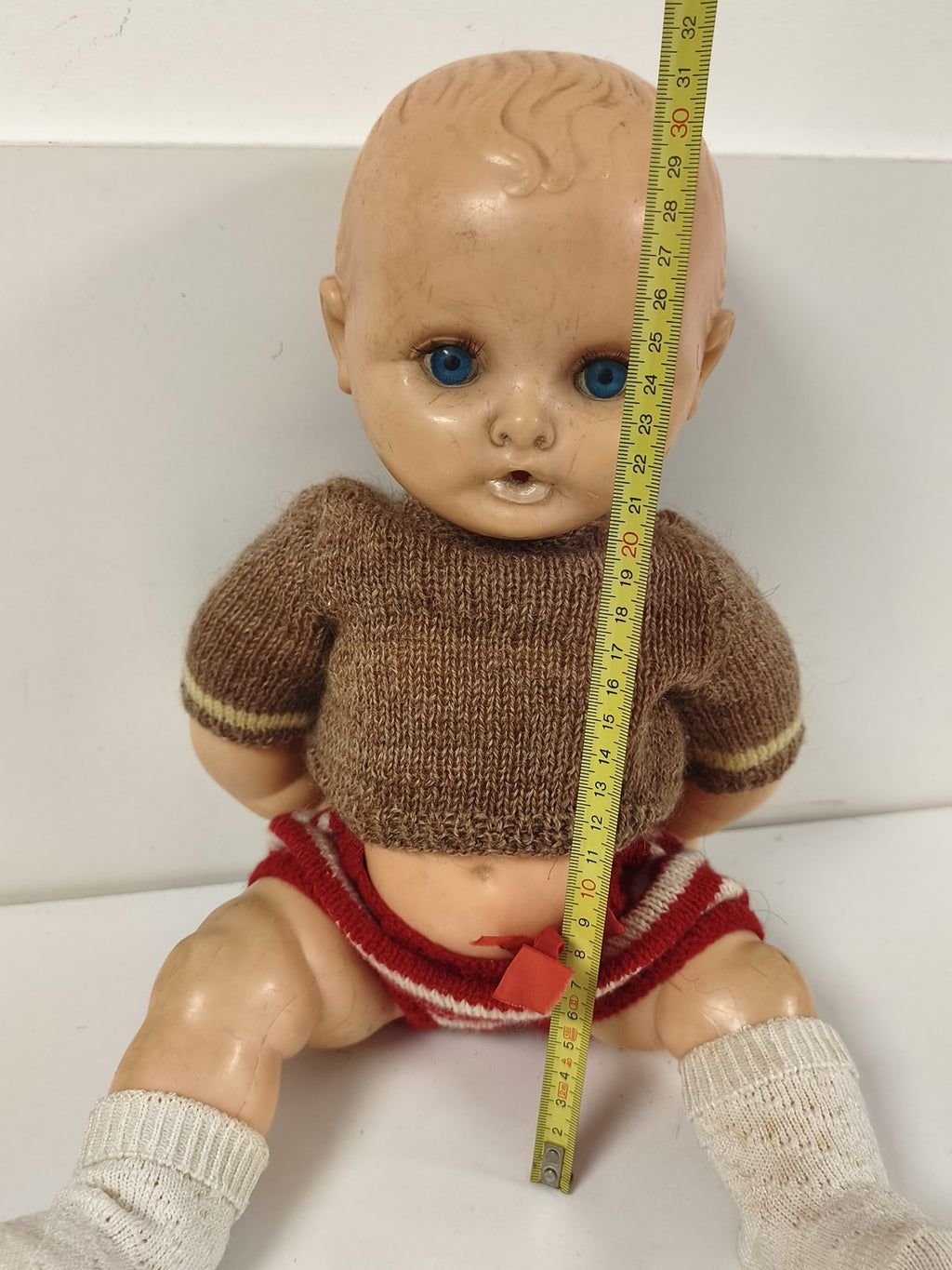 Poupée ancienne à yeux bleus, corps articulé, tenue tricotée brune