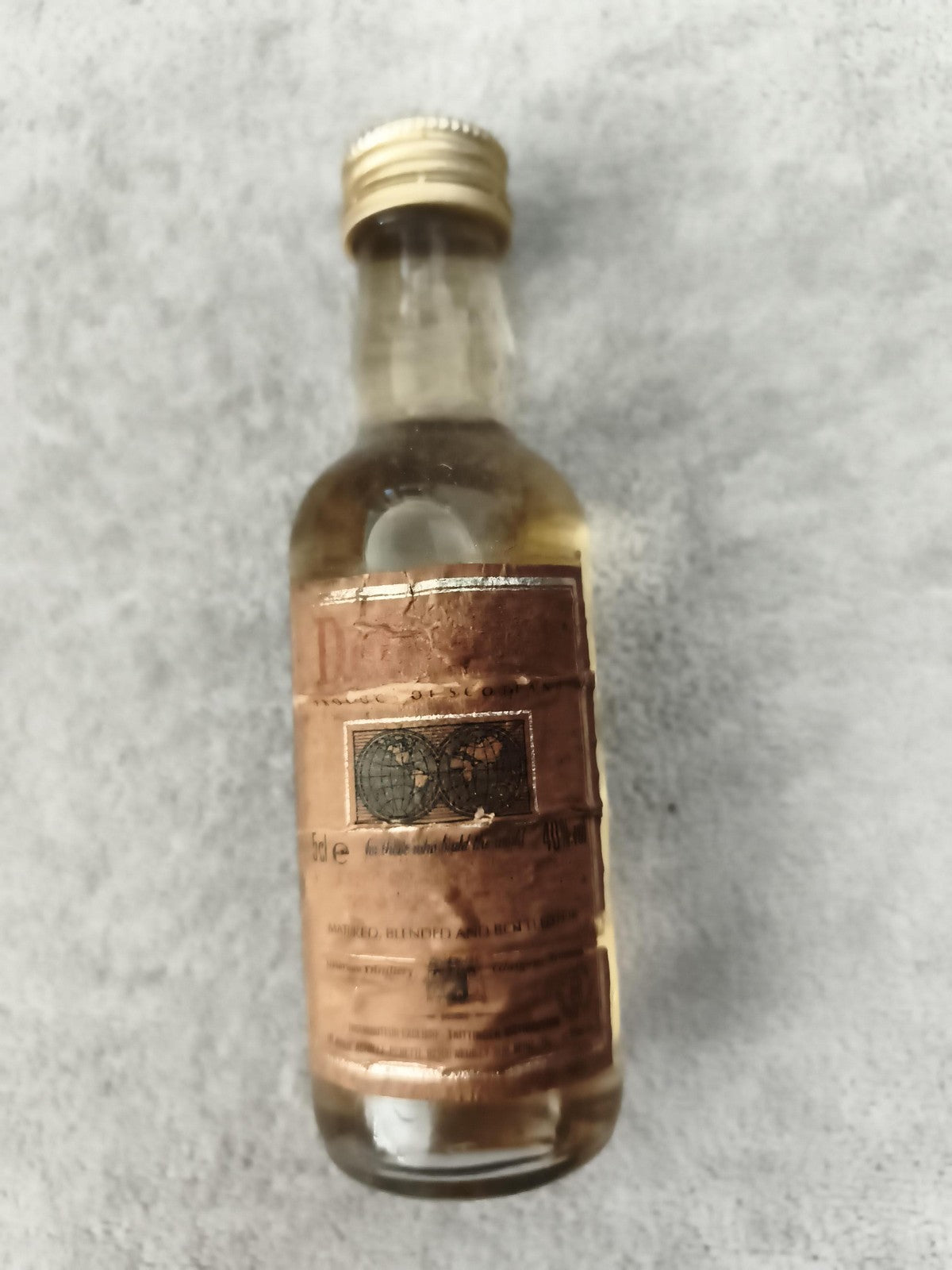 Miniature bouteille alcool étiquette marron partiellement remplie