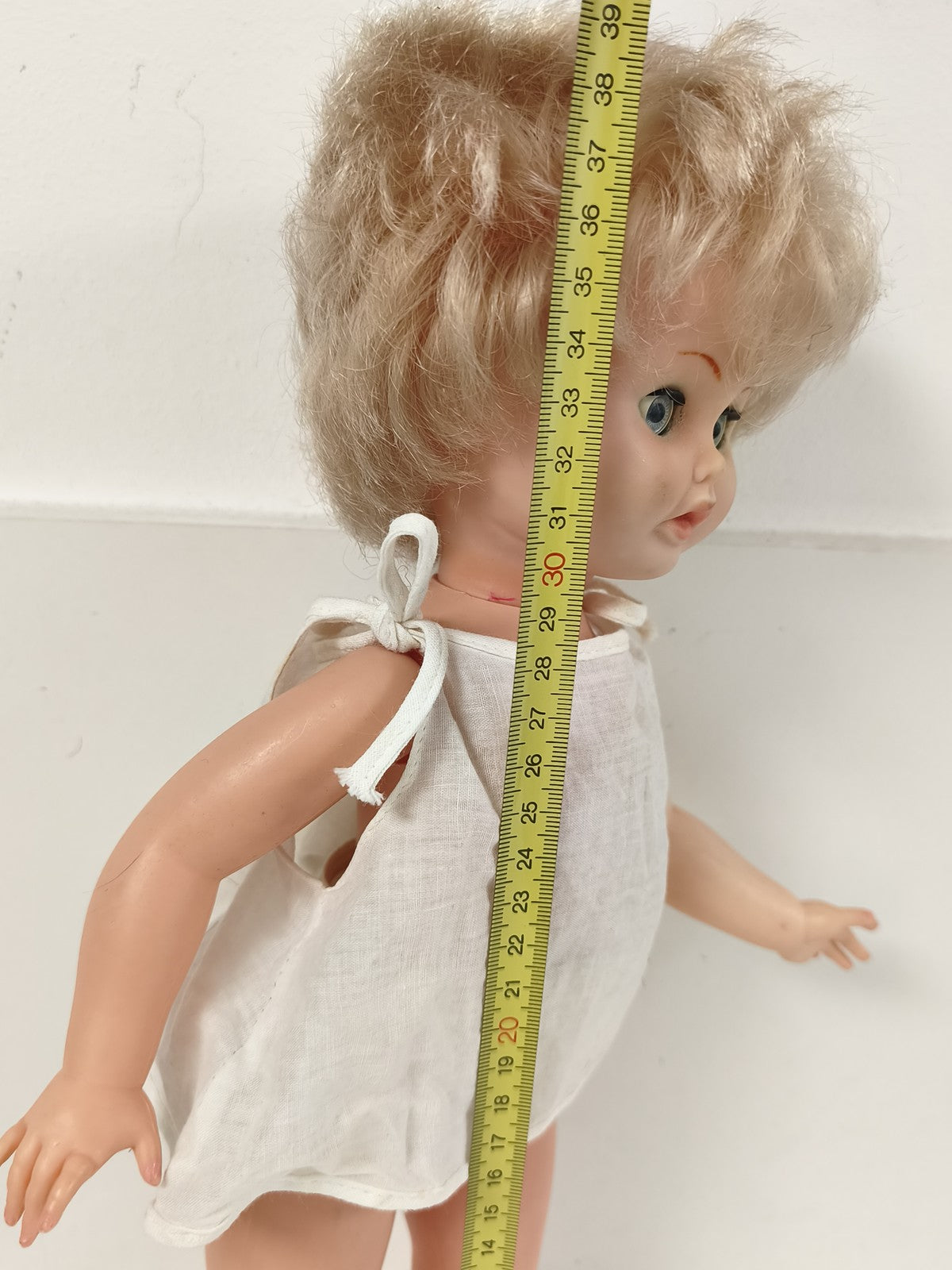 Ancienne poupée blonde aux yeux bleus, robe blanche et corps articulé