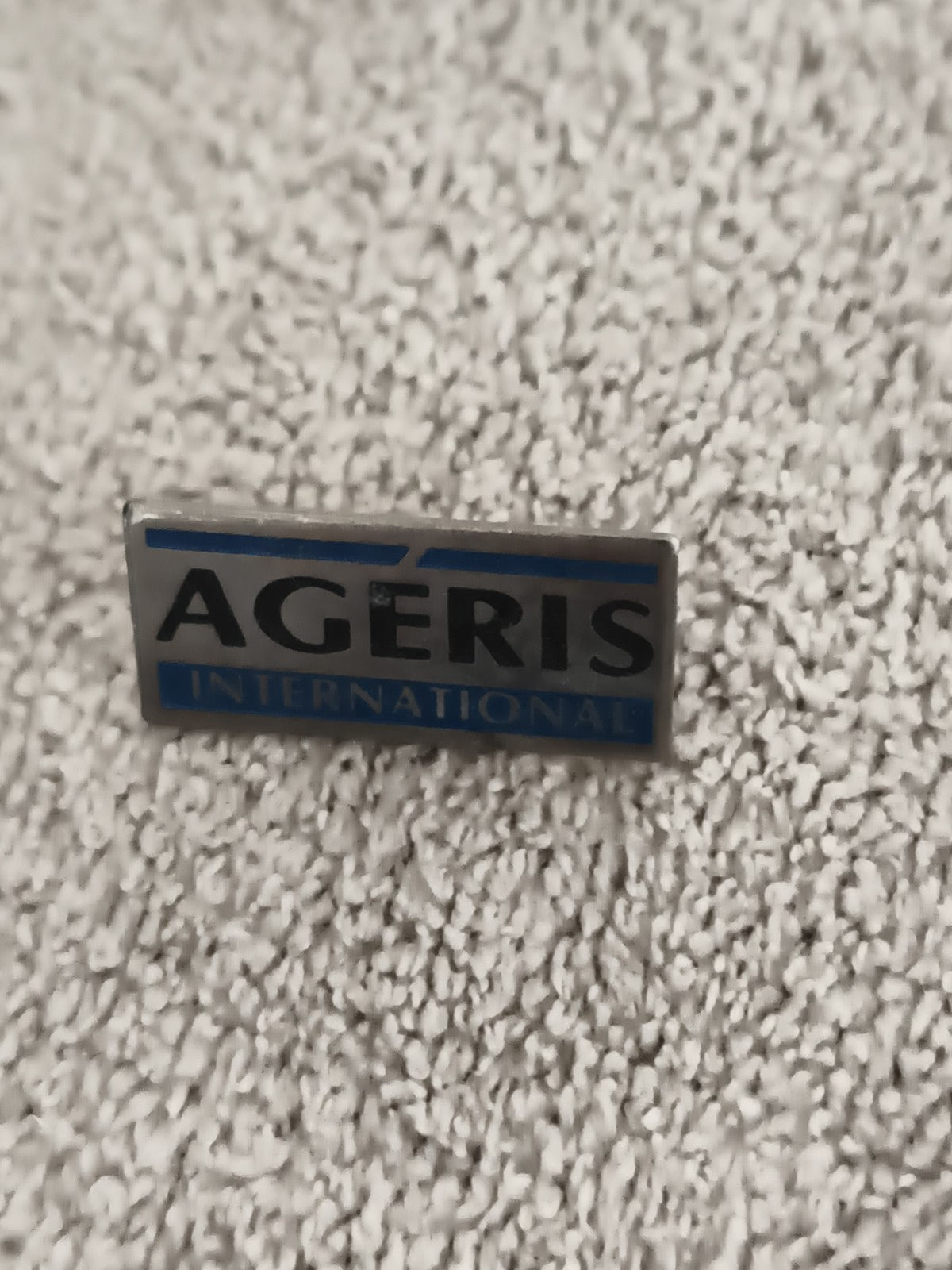 Pin's AGERIS INTERNATIONAL vintage, badge logo entreprise, aspect métal bleu (Re