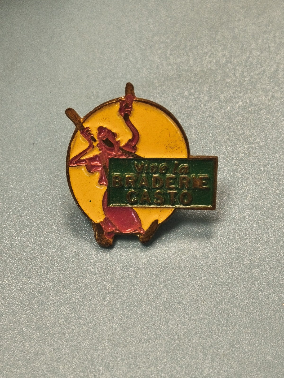 Pin's vintage braderie Casto ? personnage rose, fond jaune, collection rétro