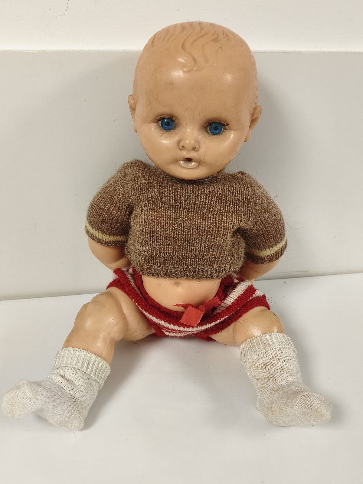 Poupée ancienne à yeux bleus, corps articulé, tenue tricotée brune